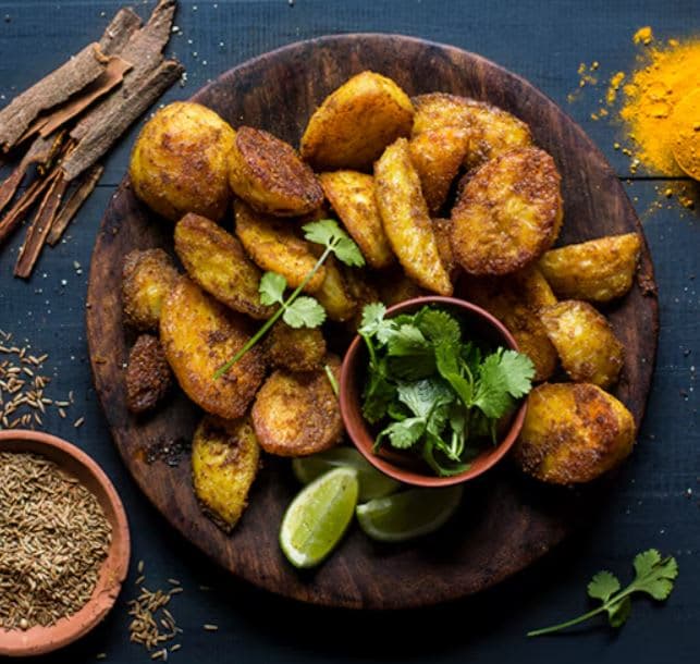 A wooden plate topped with fried food next to spices